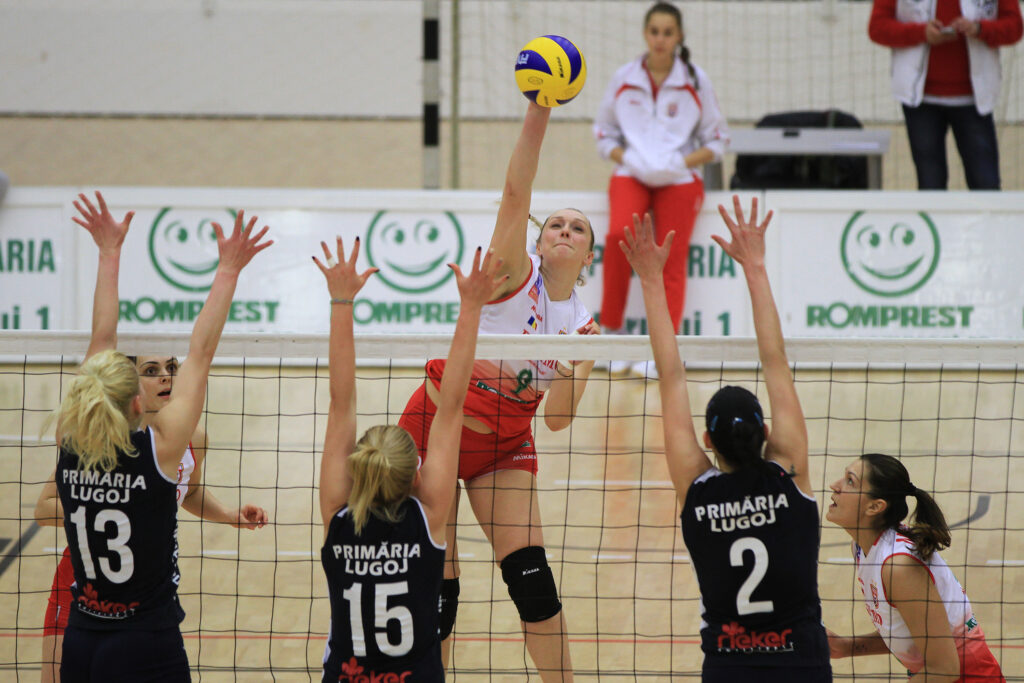 Women's volleyball game, player scores over the net.