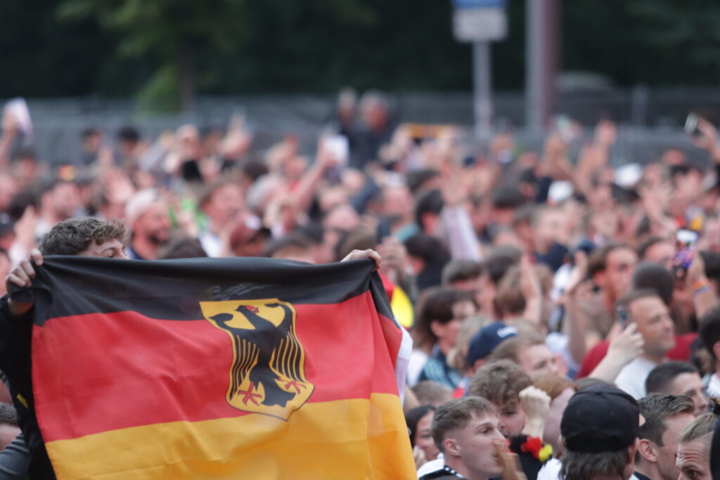 Menschenmengen in Deutschland feiern mit einer deutschen Flagge.