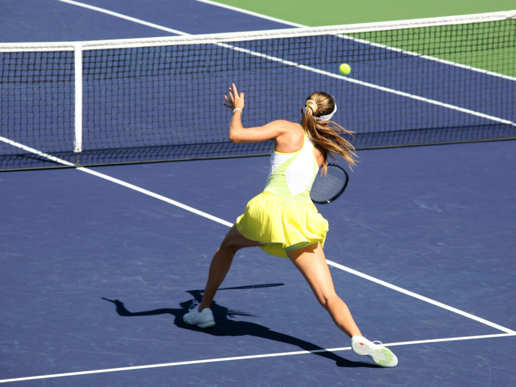 Tennisspielerin schlägt Ball auf dem Platz.