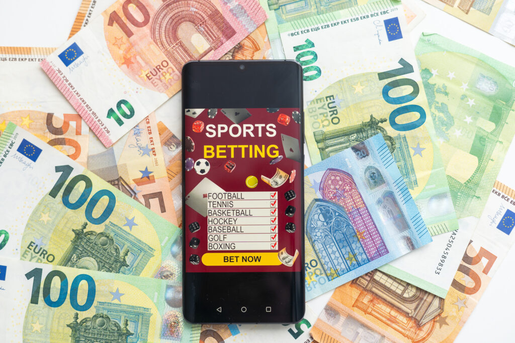 Sportwetten auf einem Handy, umgeben von Euro-Banknoten.