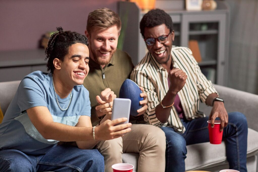 Group of three male friends watching sports match online