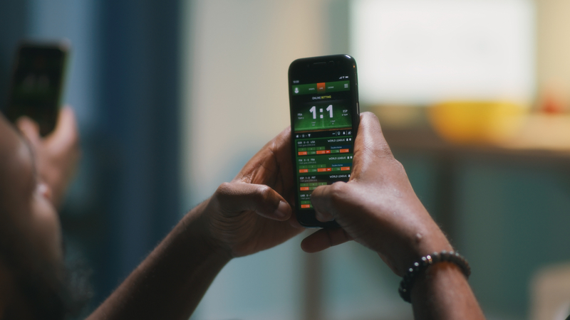 Person uses mobile phone app for betting.