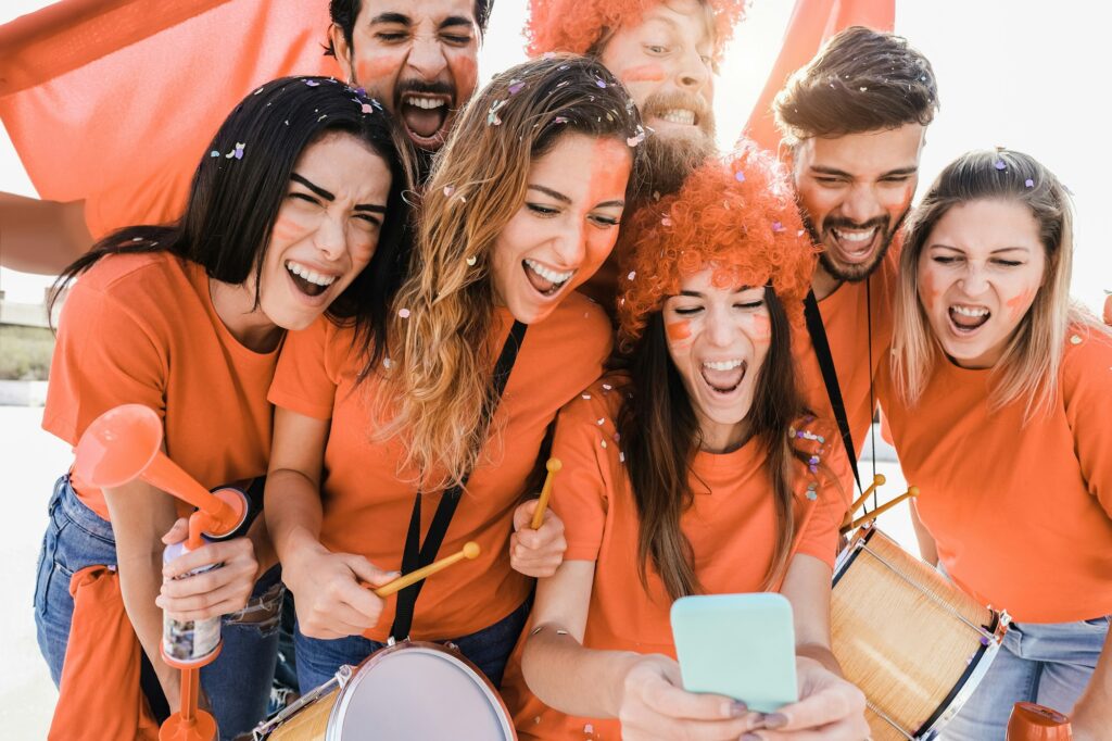 Orange sport supporters watching football game on mobile phone