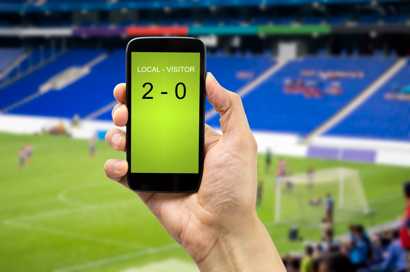 Hand holding smartphone with football score